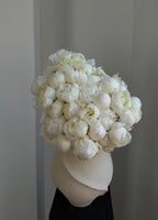 Bouquet of white peonies in a cream ceramic vase against a neutral background