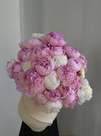 Bouquet of white peonies in a cream ceramic vase against a neutral background