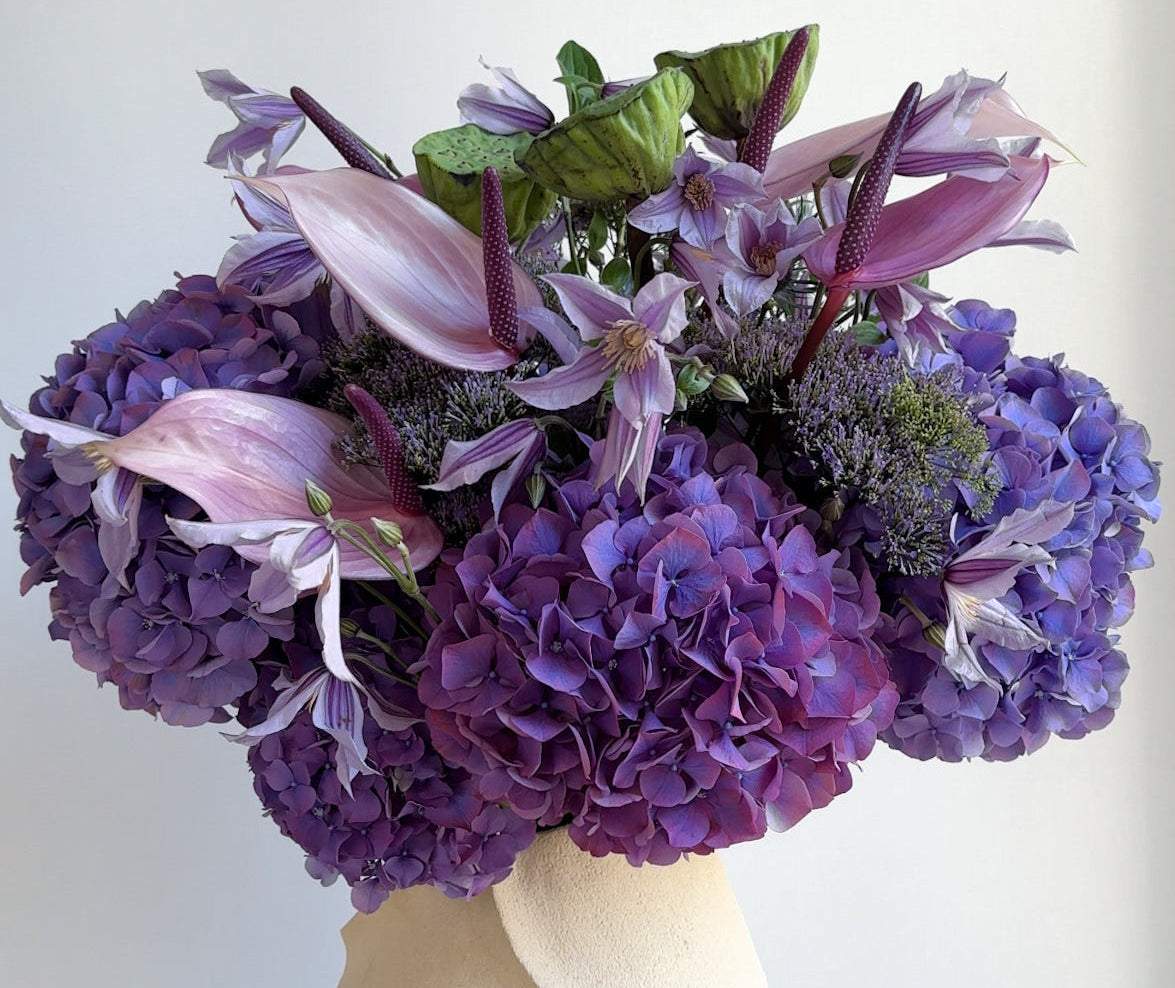 Bouquet of purple and pink flowers in a white vase on a light background