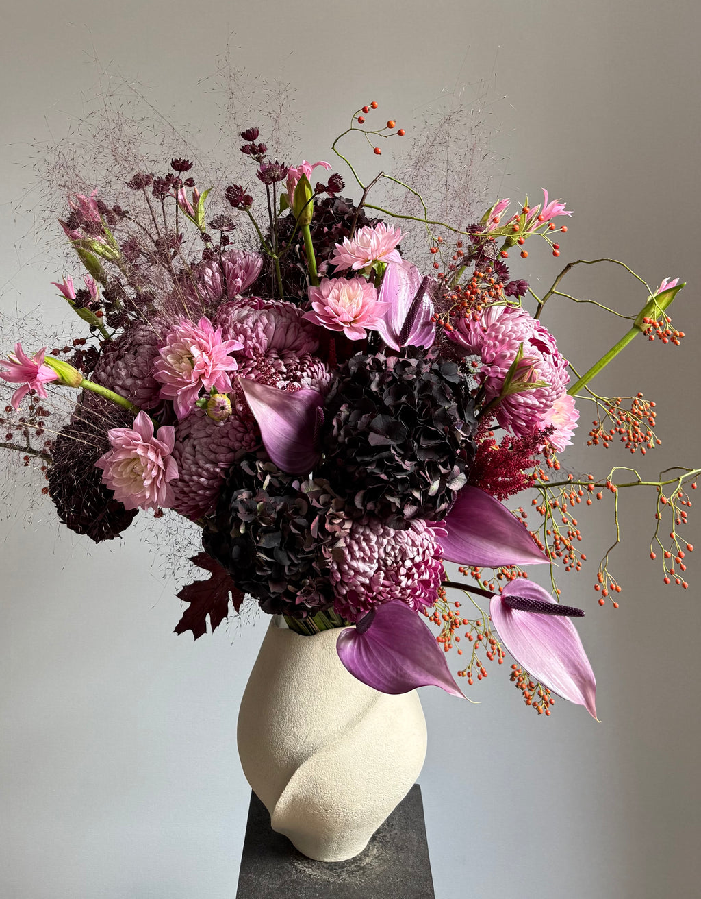 Bouquet of pink and purple flowers in a white vase on a gray background