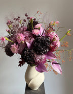 Bouquet of pink and purple flowers in a white vase on a gray background