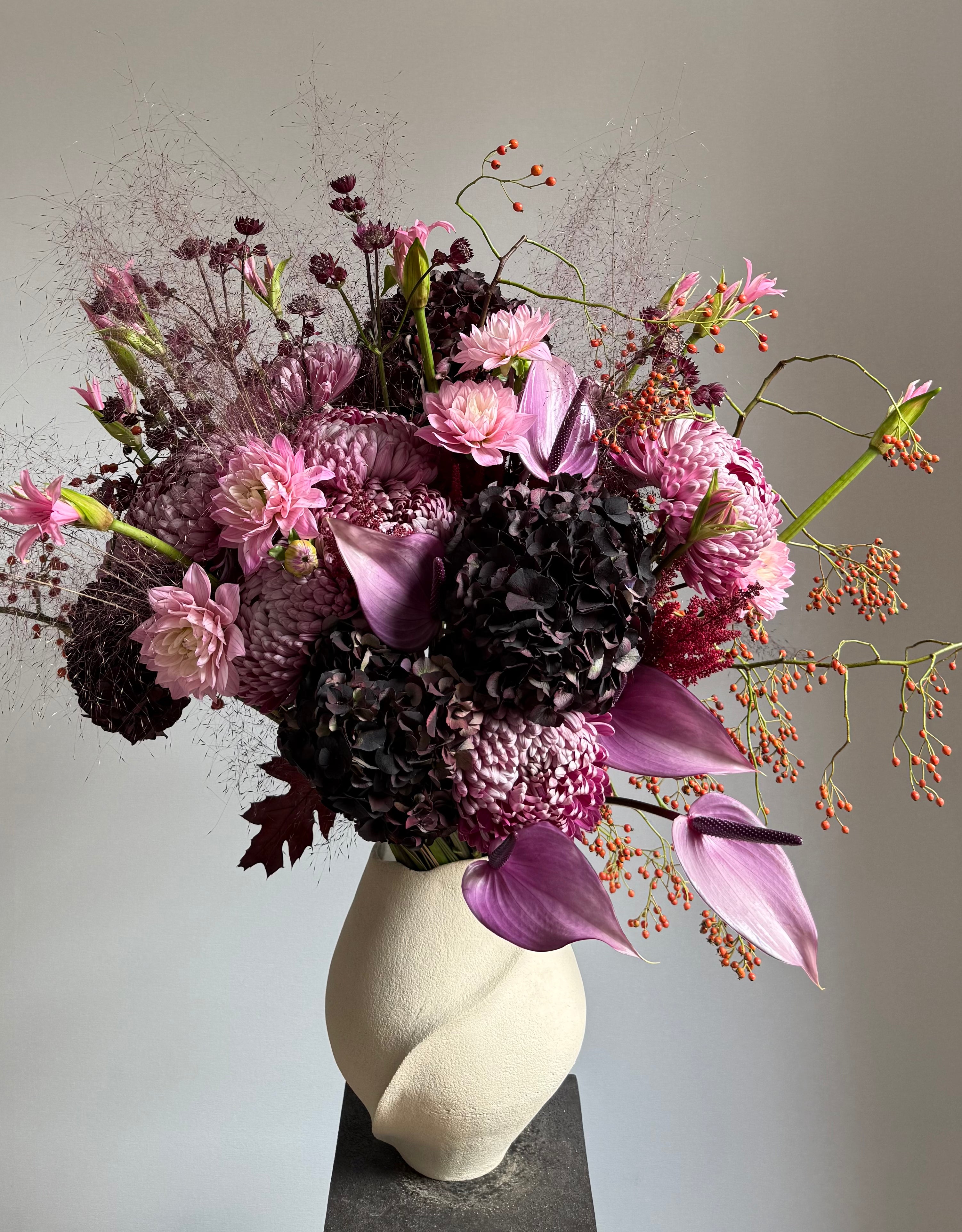 Bouquet of pink and purple flowers in a white vase on a gray background